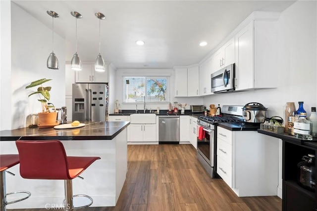 kitchen with decorative light fixtures, white cabinets, a kitchen breakfast bar, and stainless steel appliances