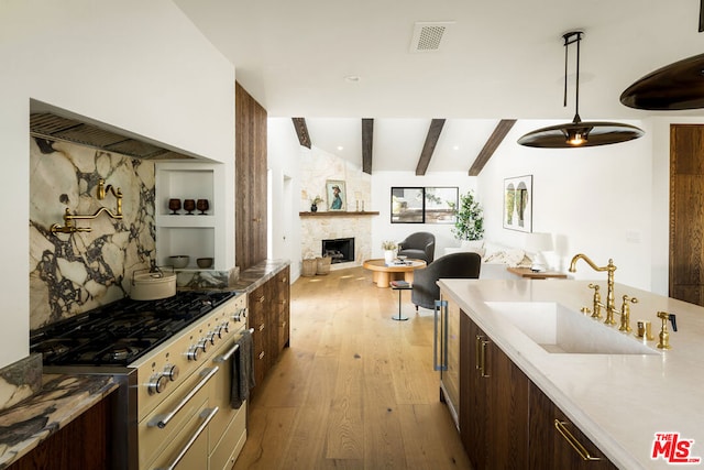 kitchen featuring light wood-type flooring, decorative light fixtures, dark brown cabinets, and sink