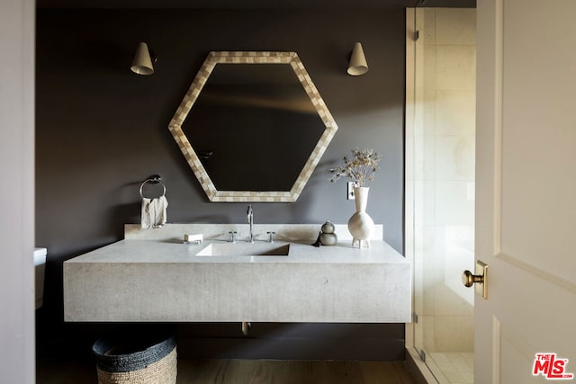 bathroom featuring sink, a shower with door, and hardwood / wood-style flooring