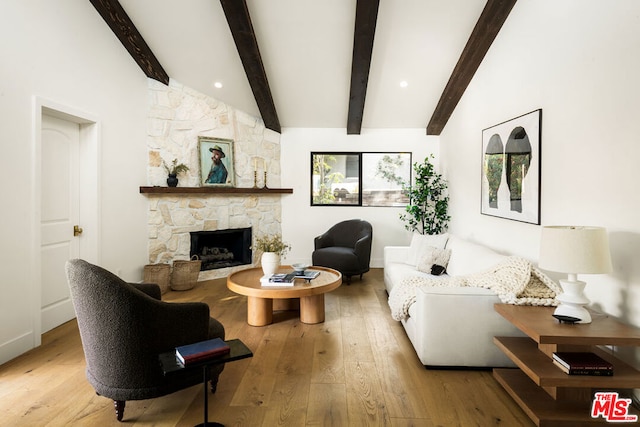 living room with light wood-type flooring, lofted ceiling with beams, and a fireplace