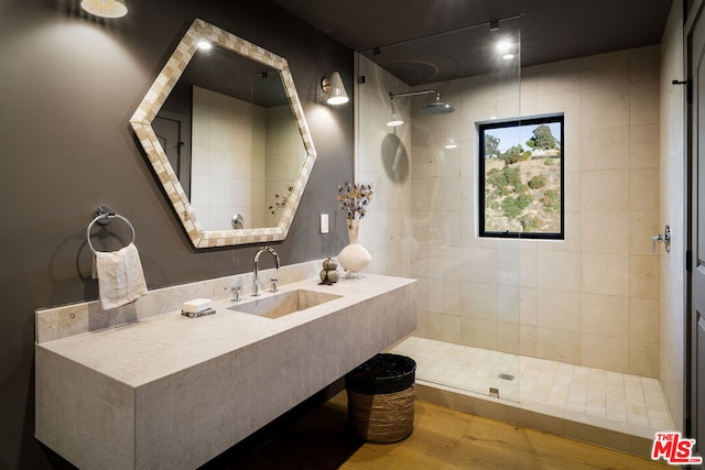 bathroom with hardwood / wood-style flooring, sink, and a tile shower