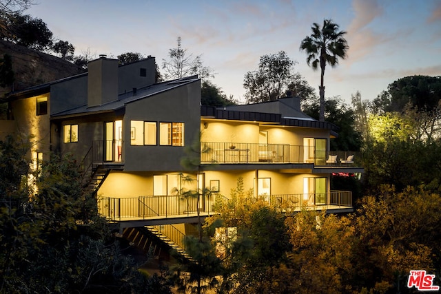 back house at dusk featuring a balcony