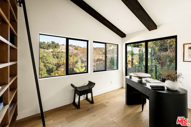 office with a wealth of natural light, light hardwood / wood-style flooring, lofted ceiling with beams, and a barn door