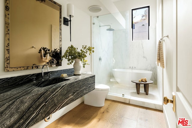 full bathroom with toilet, wood-type flooring, separate shower and tub, and sink