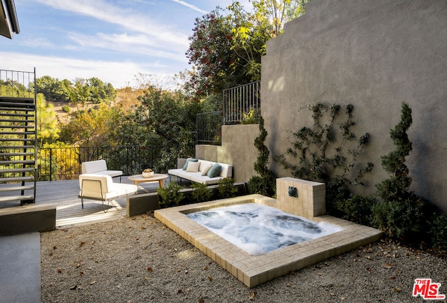 view of patio featuring outdoor lounge area, an outdoor hot tub, and a deck