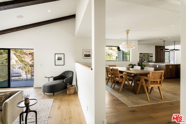 dining room with an inviting chandelier, lofted ceiling with beams, and light wood-type flooring