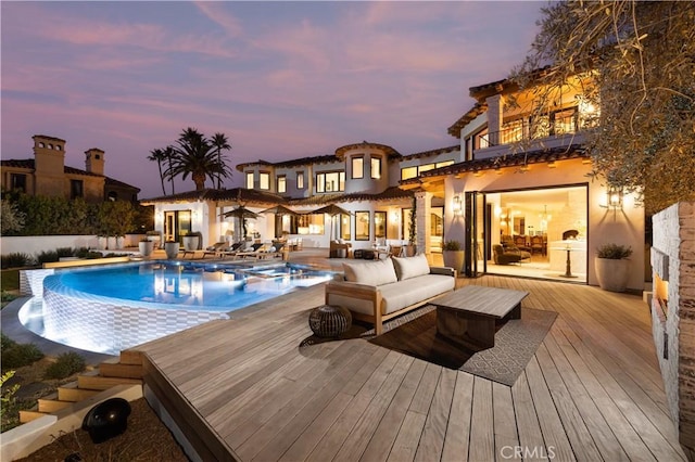 pool at dusk with a deck and outdoor lounge area