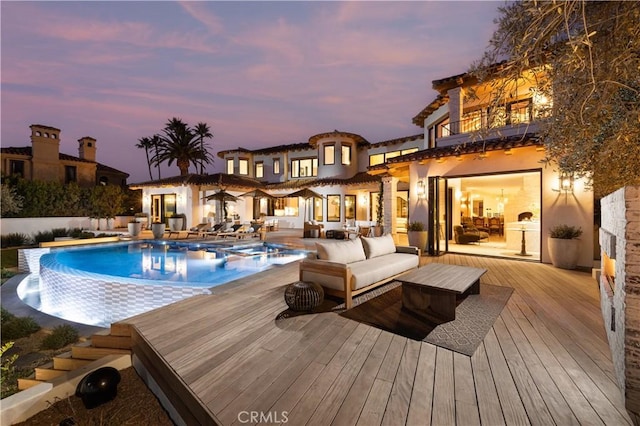 pool at dusk with a wooden deck and an outdoor living space