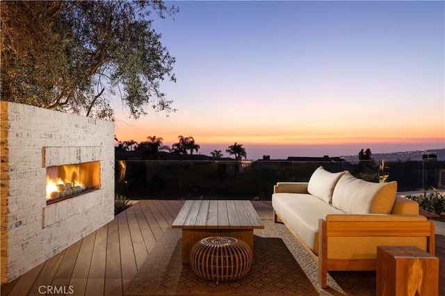 deck at dusk with an outdoor living space with a fireplace