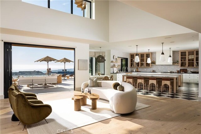 living room with a high ceiling, light hardwood / wood-style floors, and a water view