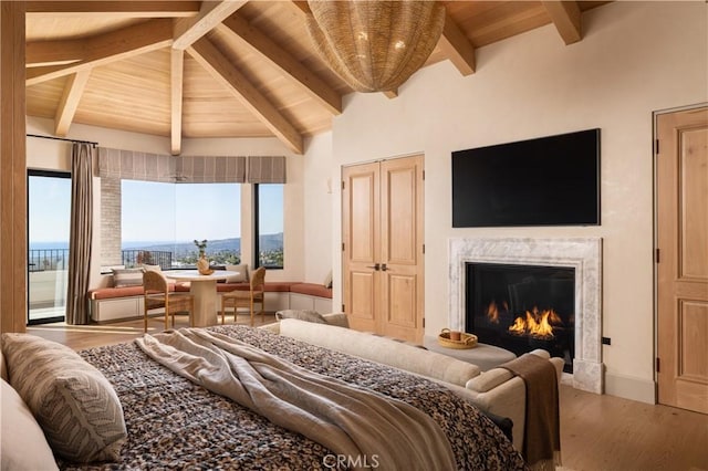 bedroom featuring a premium fireplace, vaulted ceiling with beams, wood ceiling, and hardwood / wood-style floors