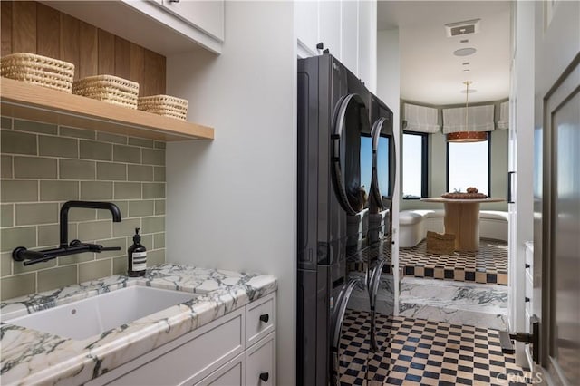 interior space with sink, white cabinetry, backsplash, and light stone counters