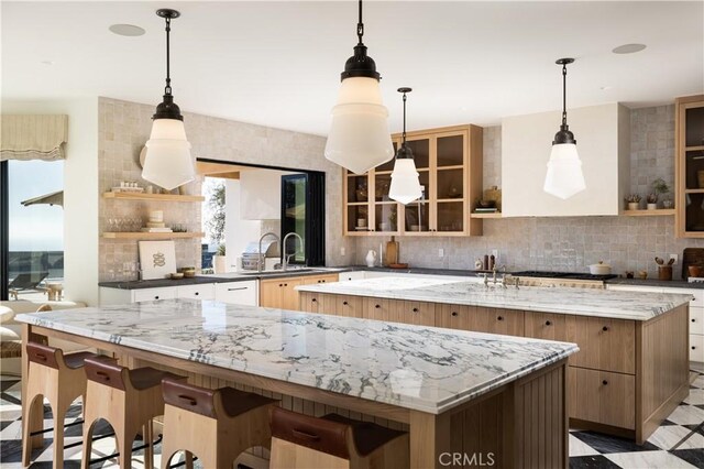 kitchen featuring pendant lighting, a large island, dark stone counters, a kitchen breakfast bar, and sink