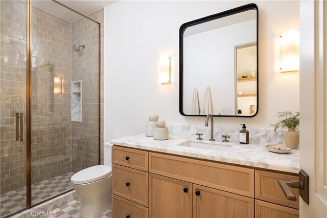 bathroom with toilet, vanity, and a shower with shower door