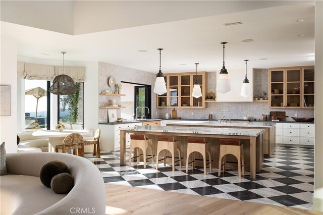 kitchen with hanging light fixtures, a kitchen bar, dark hardwood / wood-style floors, decorative backsplash, and a kitchen island