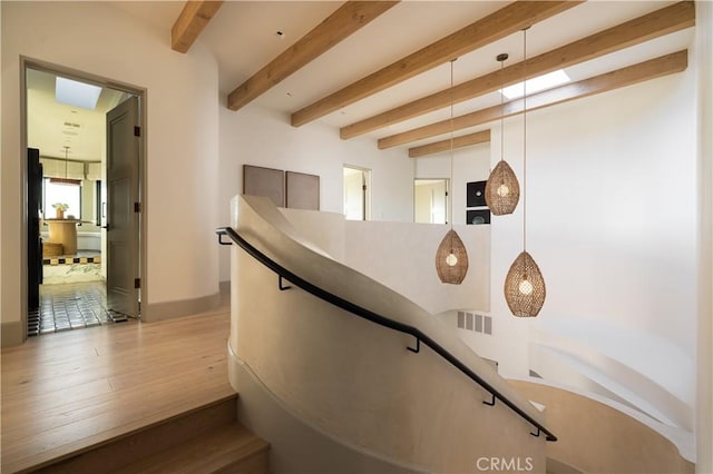 stairs featuring hardwood / wood-style flooring and beamed ceiling