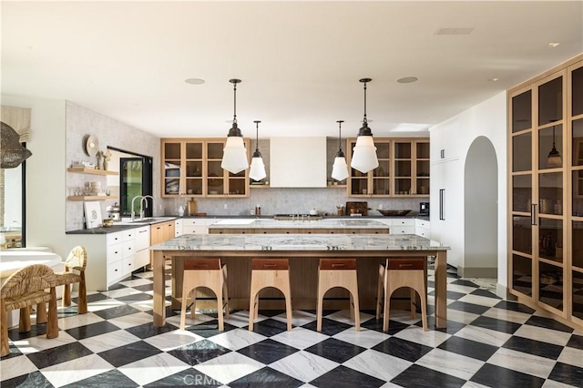 kitchen featuring a spacious island, a breakfast bar, tasteful backsplash, and sink