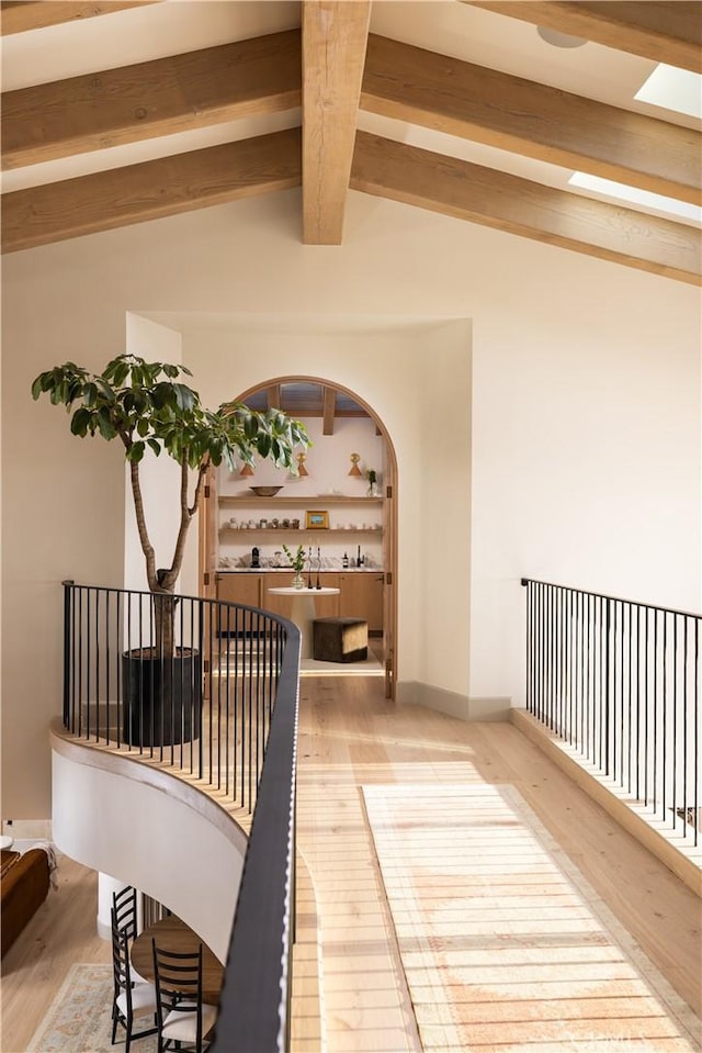 corridor with hardwood / wood-style flooring and vaulted ceiling with skylight