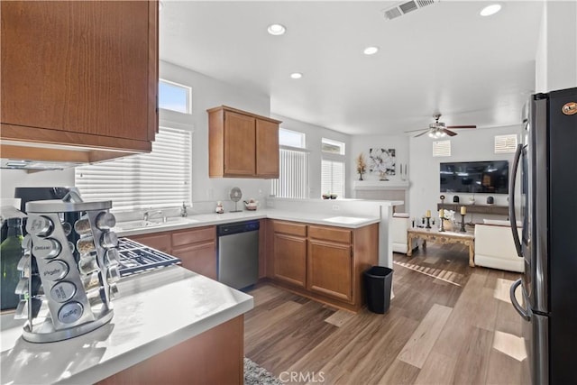 kitchen with ceiling fan, hardwood / wood-style floors, kitchen peninsula, sink, and appliances with stainless steel finishes