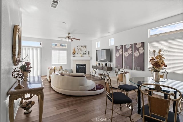 living room featuring ceiling fan, hardwood / wood-style floors, and a tiled fireplace