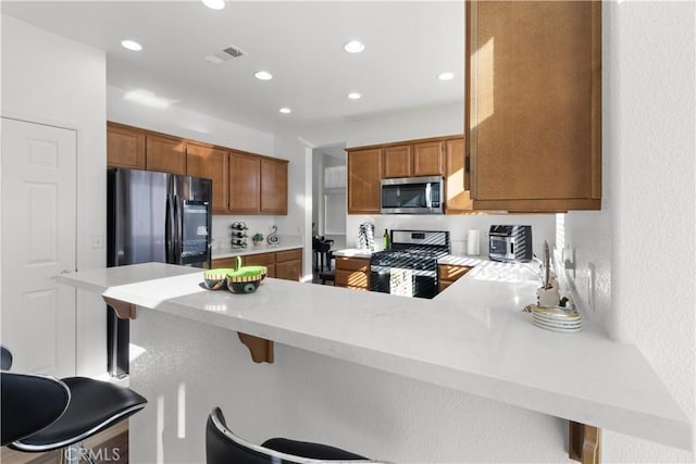 kitchen with appliances with stainless steel finishes, a kitchen bar, and kitchen peninsula