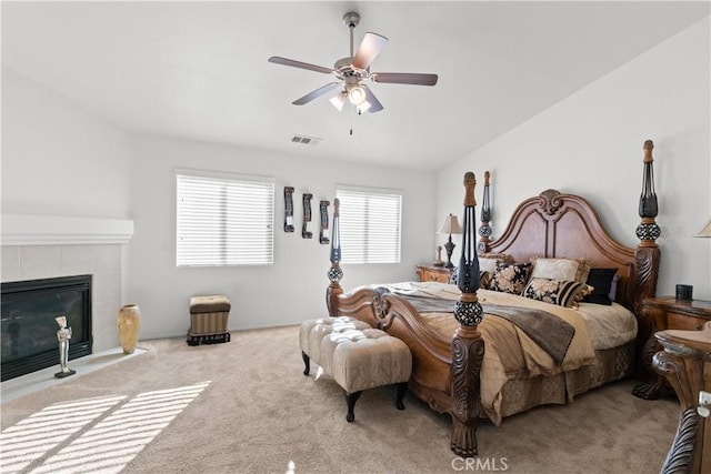 carpeted bedroom with ceiling fan, vaulted ceiling, and a fireplace