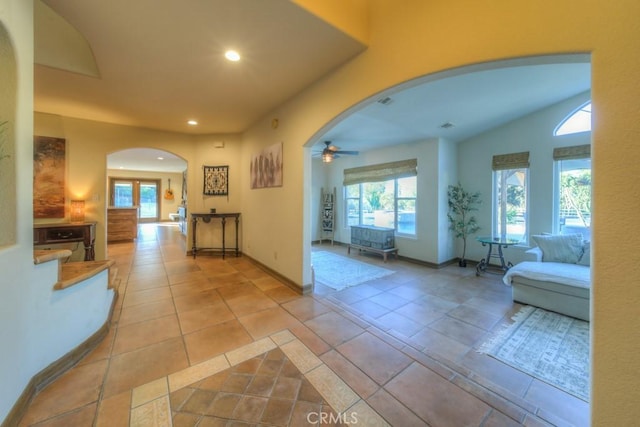 corridor with lofted ceiling, light tile patterned floors, and a wealth of natural light