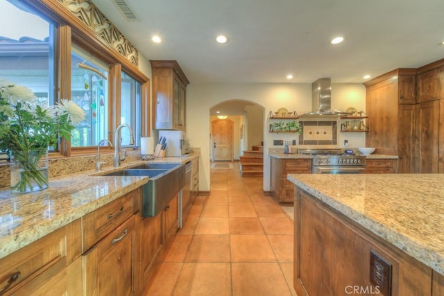 kitchen with sink, stainless steel appliances, island exhaust hood, and light stone countertops