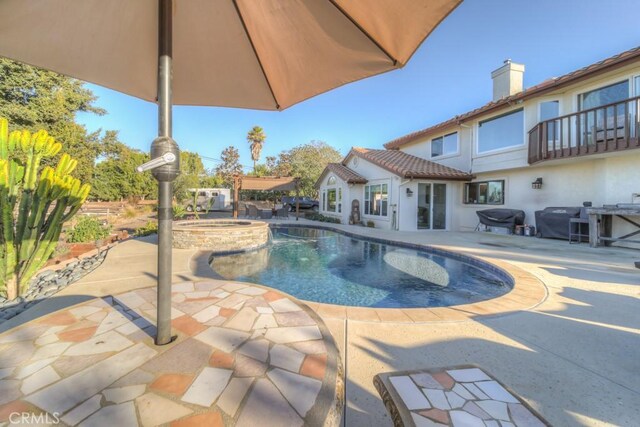 view of pool with grilling area, a patio area, and an in ground hot tub