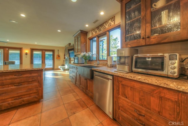 kitchen featuring sink, stainless steel dishwasher, light tile patterned flooring, and light stone countertops