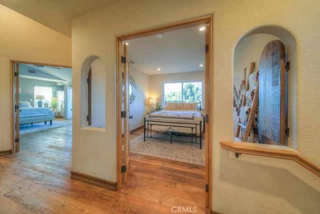 hall with light wood-type flooring and lofted ceiling