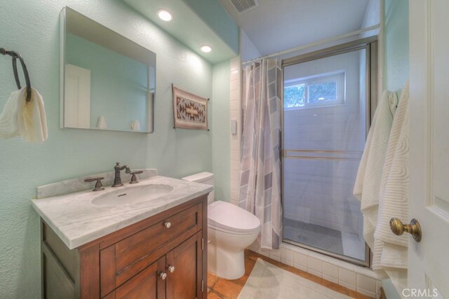 bathroom with toilet, vanity, tile patterned floors, and walk in shower