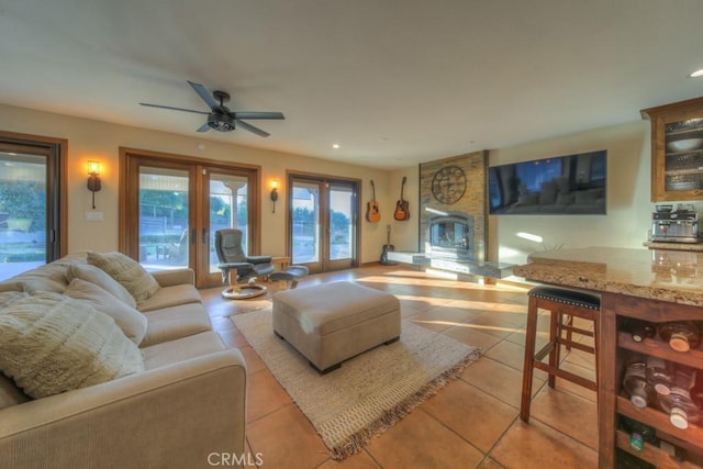 living room with ceiling fan, light tile patterned floors, french doors, and a fireplace