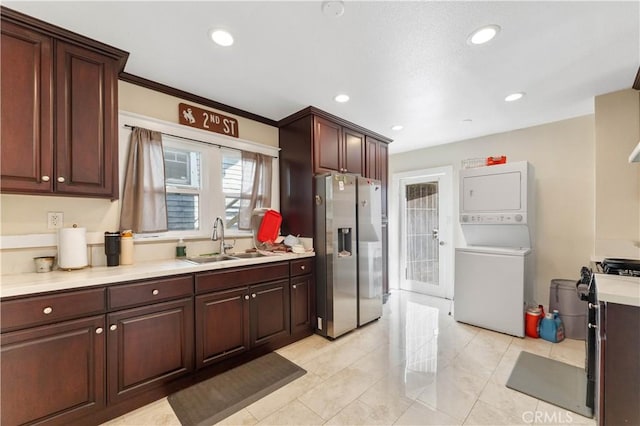 kitchen with stacked washer / drying machine, sink, ornamental molding, light tile patterned floors, and stainless steel fridge