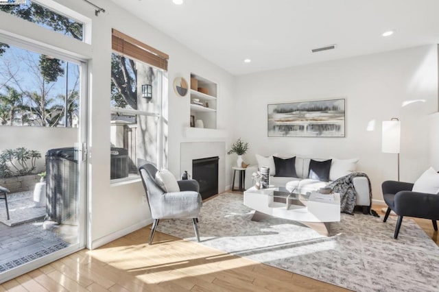 living room featuring built in shelves and light hardwood / wood-style flooring