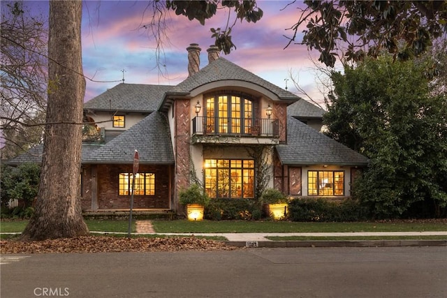 view of front of house with a balcony and a yard