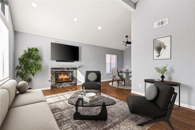 living room featuring a high end fireplace, a wealth of natural light, hardwood / wood-style floors, and ceiling fan