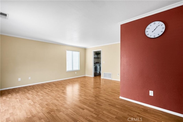 unfurnished living room with washer / clothes dryer, ornamental molding, and light hardwood / wood-style floors