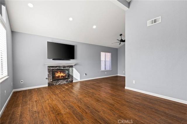 unfurnished living room featuring hardwood / wood-style flooring, ceiling fan, a wealth of natural light, and a premium fireplace