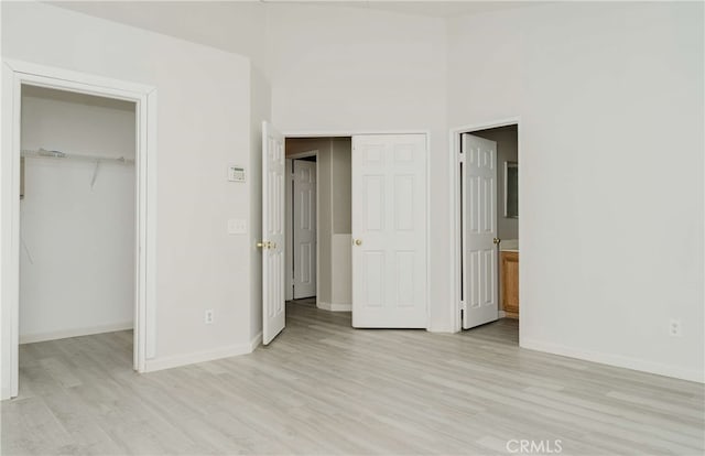 unfurnished bedroom featuring light wood-type flooring, a closet, and a walk in closet