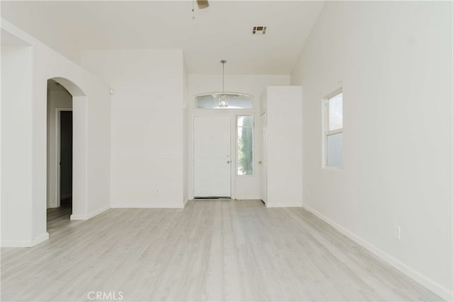 spare room with a notable chandelier and light hardwood / wood-style flooring