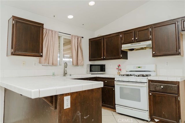 kitchen with kitchen peninsula, light tile patterned flooring, lofted ceiling, dark brown cabinets, and white gas range