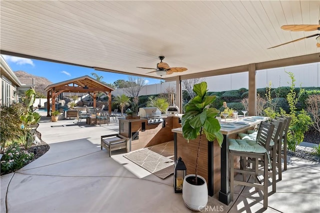 view of patio / terrace featuring an outdoor kitchen, a gazebo, grilling area, and ceiling fan