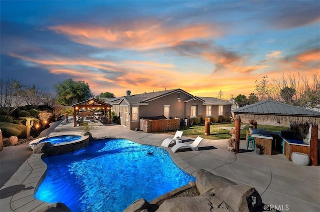 pool at dusk featuring a bar, a patio, an in ground hot tub, and a gazebo