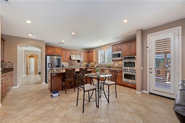 kitchen featuring appliances with stainless steel finishes, a breakfast bar, tasteful backsplash, and a center island