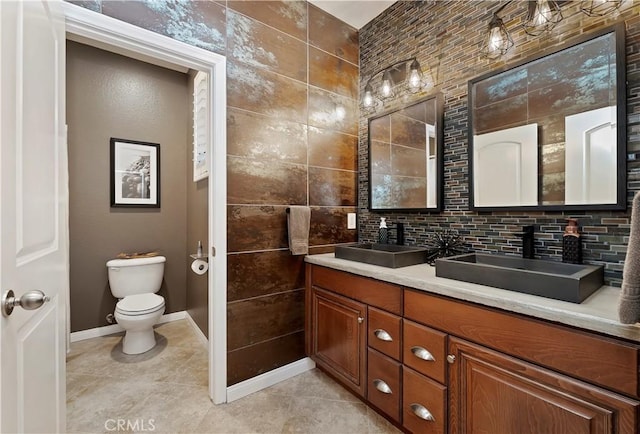 bathroom with toilet, vanity, tile patterned floors, and tasteful backsplash