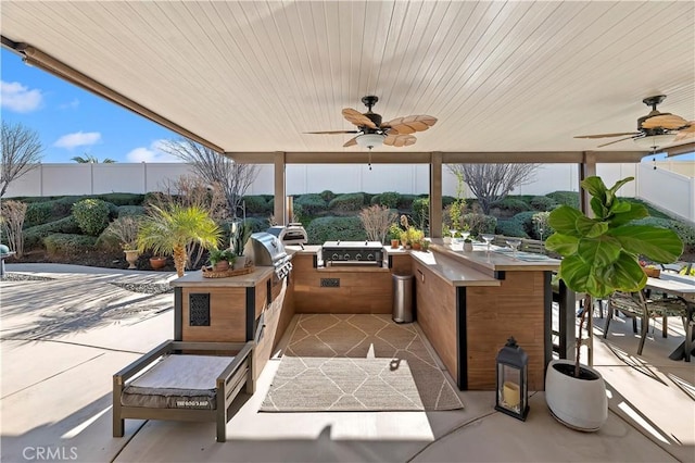 view of patio with ceiling fan, area for grilling, an outdoor bar, and an outdoor kitchen