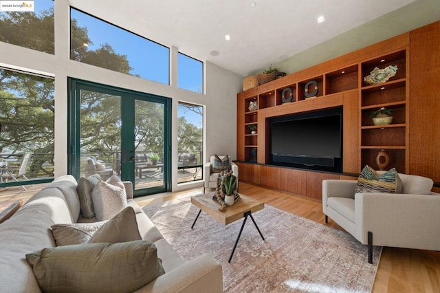 living room featuring a high ceiling, french doors, and light wood-type flooring