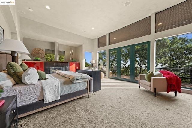 carpeted bedroom featuring access to exterior, a towering ceiling, and french doors