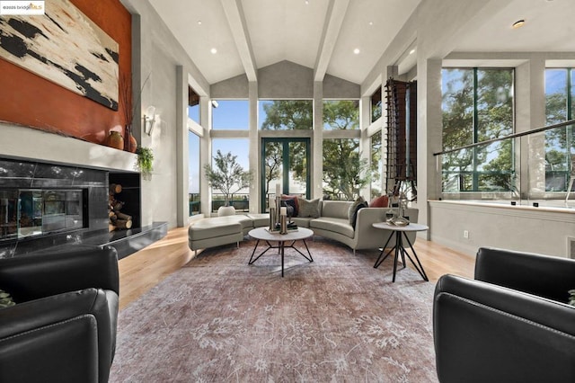 living room featuring lofted ceiling with beams, a premium fireplace, and light hardwood / wood-style flooring